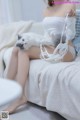 A woman sitting on a bed holding a white cat.