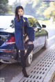 A woman leaning against a car on the side of the road.