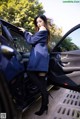 A woman standing next to a car with the door open.