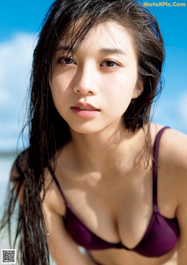 A woman in a purple bikini sitting on the beach.