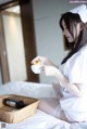 A woman sitting on a bed holding a cup of coffee.