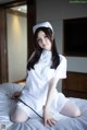 A woman in a white nurse outfit sitting on a bed.