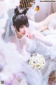 A woman in a wedding dress holding a bouquet of flowers.