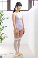 A woman in a purple leotard and white stockings standing on a scale.