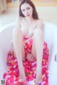 A woman sitting in a bathtub filled with rose petals.