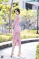 A woman in a pink dress is walking down the street.