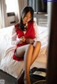 A woman sitting on a bed with a phone in her hand.