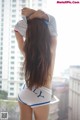 A woman in a white shirt and blue shorts standing on a balcony.