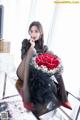 A woman sitting on a chair holding a bouquet of red roses.