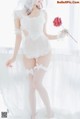 A woman in a white lingerie holding a red rose.