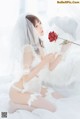 A woman in a white lingerie holding a red rose.