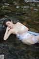 A woman in a white lingerie laying in a stream.