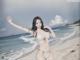 A woman in a white bikini standing on a beach.