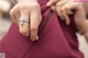 A woman in a maroon dress holding a diamond ring.