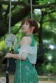 A woman in a green dress holding a fan.