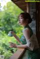 A woman in a green dress holding a teapot.