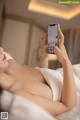 A woman laying in bed holding a cell phone up to her face.