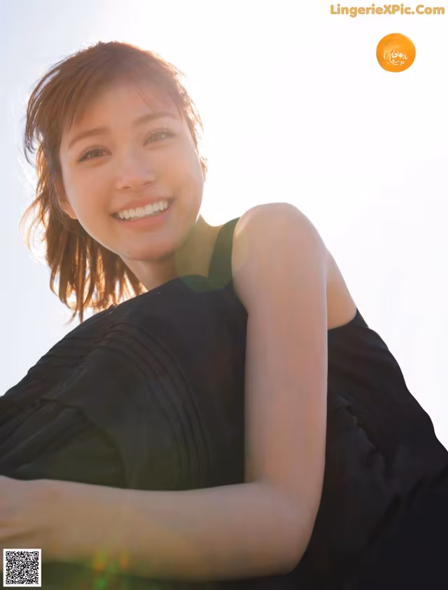 A woman in a black dress smiling at the camera.