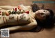 A naked woman laying on a wooden floor covered in sushi.