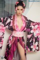 A woman in a pink and black kimono posing for a picture.