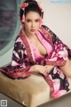 A woman in a pink and black kimono sitting on a couch.