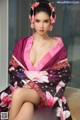 A woman in a pink and black kimono sitting on a couch.