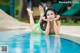 A woman in a green bikini laying on the edge of a pool.